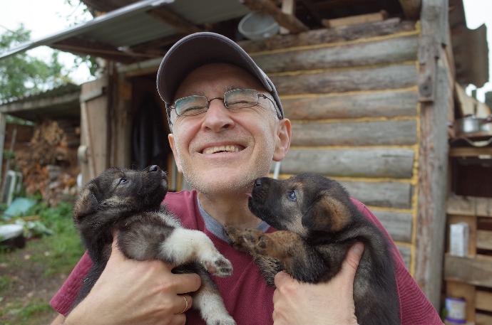 Smiling man holding 2 gorgeous Puppys